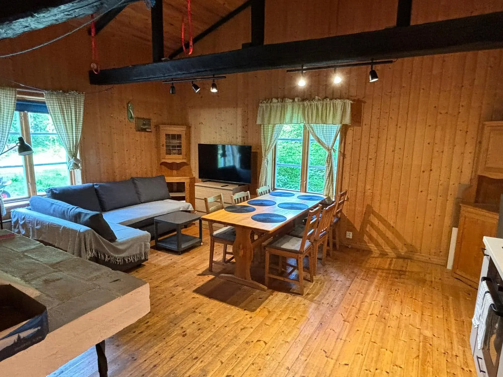 Large cabin living area with a sofa, dining table for six and a view towards the kitchen